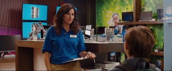 Movie still from “Good Boys” (2019), directed by Gene Stupnitsky – A woman standing in front of a counter holding a clipboard; Medium shot, Over the shoulder angle