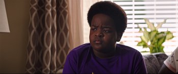 Movie still from “Good Boys” (2019), directed by Gene Stupnitsky – A young black boy in a purple t - shirt looking sad; Close Up shot, Over the shoulder angle