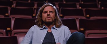 Movie still from “Good Boys” (2019), directed by Gene Stupnitsky – A man with long hair and beard sitting in front of an audience; Medium shot, Low angle