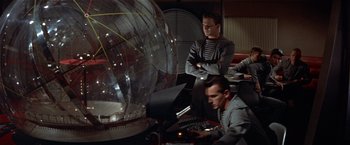Movie still from “Forbidden Planet” (1956), directed by Fred M. Wilcox – A group of men working on computers next to an object; Medium shot, Low angle