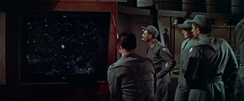 Movie still from “Forbidden Planet” (1956), directed by Fred M. Wilcox – Two men are looking at a television screen; Medium shot, High angle