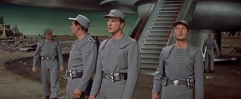 Movie still from “Forbidden Planet” (1956), directed by Fred M. Wilcox – A group of men standing next to each other wearing uniforms; Medium shot, Low angle