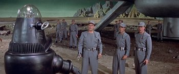 Movie still from “Forbidden Planet” (1956), directed by Fred M. Wilcox – A group of men standing next to each other in a field; Wide shot, Low angle