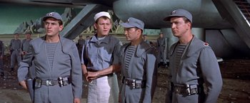 Movie still from “Forbidden Planet” (1956), directed by Fred M. Wilcox – A group of men standing next to each other in uniforms; Medium shot, Over the shoulder angle