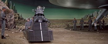 Movie still from “Forbidden Planet” (1956), directed by Fred M. Wilcox – A robot is sitting on top of a pile of metal; Extreme Wide shot, Low angle