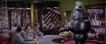 Movie still from “Forbidden Planet” (1956), directed by Fred M. Wilcox – A group of men sitting at a table drinking from cups; Wide shot, Over the shoulder angle
