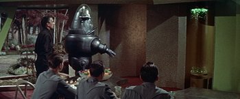Movie still from “Forbidden Planet” (1956), directed by Fred M. Wilcox – A group of people sitting around a table; Medium shot, Low angle