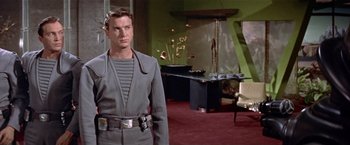 Movie still from “Forbidden Planet” (1956), directed by Fred M. Wilcox – A man in a gray suit stands in a room; Medium shot, Low angle