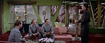 Movie still from “Forbidden Planet” (1956), directed by Fred M. Wilcox – A couple of men sitting on top of a pink couch; Wide shot, Low angle