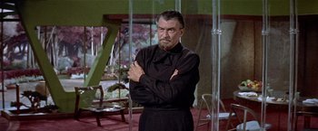 Movie still from “Forbidden Planet” (1956), directed by Fred M. Wilcox – A man standing in a room with his arms crossed; Medium shot, Low angle