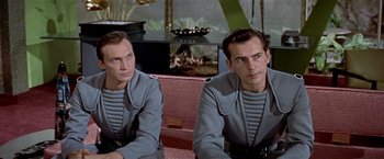 Movie still from “Forbidden Planet” (1956), directed by Fred M. Wilcox – A couple of men sitting next to each other in a room; Medium shot, Over the shoulder angle