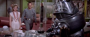 Movie still from “Forbidden Planet” (1956), directed by Fred M. Wilcox – Two men in grey suits standing in front of a robot; Medium shot, Over the shoulder angle