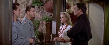 Movie still from “Forbidden Planet” (1956), directed by Fred M. Wilcox – A group of people standing next to each other near rocks; Medium shot, Over the shoulder angle