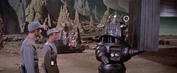 Movie still from “Forbidden Planet” (1956), directed by Fred M. Wilcox – A man standing next to a robot in a field; Wide shot, High angle