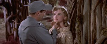 Movie still from “Forbidden Planet” (1956), directed by Fred M. Wilcox – A man in a military uniform putting lipstick on a woman's face; Close Up shot, Low angle