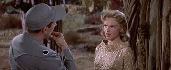Movie still from “Forbidden Planet” (1956), directed by Fred M. Wilcox – A woman in a gold dress talking to a man in a uniform; Medium shot, Over the shoulder angle
