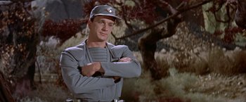 Movie still from “Forbidden Planet” (1956), directed by Fred M. Wilcox – A man in a uniform standing in front of a tree; Medium shot, Low angle