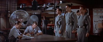 Movie still from “Forbidden Planet” (1956), directed by Fred M. Wilcox – A group of men standing next to each other in a room; Medium shot, Low angle
