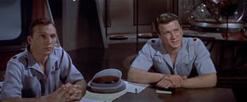 Movie still from “Forbidden Planet” (1956), directed by Fred M. Wilcox – A man sitting at a table in front of another man; Medium shot, Over the shoulder angle