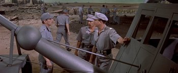 Movie still from “Forbidden Planet” (1956), directed by Fred M. Wilcox – A group of men standing next to each other near an airplane; Wide shot, High angle