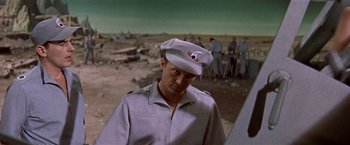 Movie still from “Forbidden Planet” (1956), directed by Fred M. Wilcox – A man wearing a hat standing in front of a group of people; Medium shot, Low angle