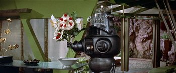 Movie still from “Forbidden Planet” (1956), directed by Fred M. Wilcox – An old fashion looking coffee pot sitting next to flowers; Medium shot, Low angle