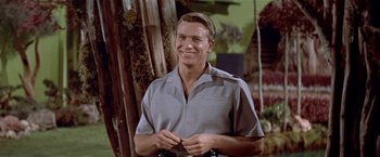 Movie still from “Forbidden Planet” (1956), directed by Fred M. Wilcox – A man smiling while standing in front of a tree; Close Up shot, Low angle