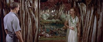 Movie still from “Forbidden Planet” (1956), directed by Fred M. Wilcox – A woman standing in front of a painting of a forest; Wide shot, High angle