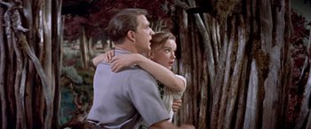 Movie still from “Forbidden Planet” (1956), directed by Fred M. Wilcox – A man and a woman are hugging in the woods; Medium shot, Low angle