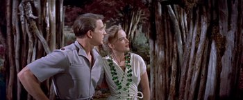 Movie still from “Forbidden Planet” (1956), directed by Fred M. Wilcox – A man and a woman standing next to each other in front of a tree; Medium shot, Low angle