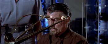 Movie still from “Forbidden Planet” (1956), directed by Fred M. Wilcox – An older man wearing a brown shirt and a pair of glasses; Close Up shot, High angle