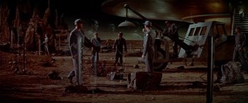 Movie still from “Forbidden Planet” (1956), directed by Fred M. Wilcox – A group of people standing on top of a dirt field; Wide shot, High angle