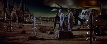 Movie still from “Forbidden Planet” (1956), directed by Fred M. Wilcox – A group of men standing on top of a dirt field; Extreme Wide shot, High angle