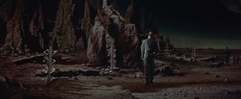 Movie still from “Forbidden Planet” (1956), directed by Fred M. Wilcox – A man standing in front of a large rock formation; Extreme Wide shot, High angle