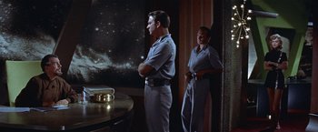 Movie still from “Forbidden Planet” (1956), directed by Fred M. Wilcox – A man and a woman standing in front of a projection screen; Medium shot, Over the shoulder angle