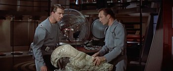 Movie still from “Forbidden Planet” (1956), directed by Fred M. Wilcox – Two men in a lab looking at an object; Medium shot, Low angle
