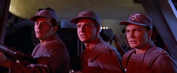 Movie still from “Forbidden Planet” (1956), directed by Fred M. Wilcox – A group of men standing next to each other in a room; Medium shot, Low angle