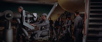 Movie still from “Forbidden Planet” (1956), directed by Fred M. Wilcox – A group of men standing next to each other in a room; Wide shot, High angle