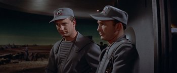 Movie still from “Forbidden Planet” (1956), directed by Fred M. Wilcox – A couple of men standing next to each other; Medium shot, Low angle