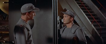 Movie still from “Forbidden Planet” (1956), directed by Fred M. Wilcox – A man in a uniform looking at himself in the mirror; Medium shot, Over the shoulder angle