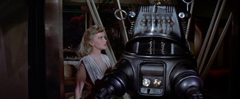 Movie still from “Forbidden Planet” (1956), directed by Fred M. Wilcox – A woman standing in front of a large robot; Medium shot, Low angle