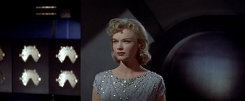 Movie still from “Forbidden Planet” (1956), directed by Fred M. Wilcox – A woman with blonde hair wearing a gray dress; Medium shot, Low angle