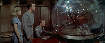Movie still from “Forbidden Planet” (1956), directed by Fred M. Wilcox – Two men are sitting at a table in front of a globe; Medium shot, Low angle