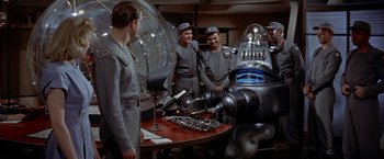 Movie still from “Forbidden Planet” (1956), directed by Fred M. Wilcox – A group of men standing next to each other in a room; Wide shot, High angle