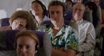 Movie still from “Forgetting Sarah Marshall” (2008), directed by Nicholas Stoller – A group of people sitting on a plane wearing headphones; Medium shot, Over the shoulder angle
