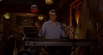 Movie still from “Forgetting Sarah Marshall” (2008), directed by Nicholas Stoller – A man standing at a keyboard in front of microphones; Medium shot, Over the shoulder angle