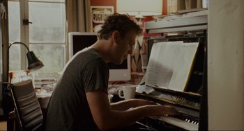 Movie still from “Forgetting Sarah Marshall” (2008), directed by Nicholas Stoller – A man sitting at a piano in front of a computer screen; Medium shot, Over the shoulder angle