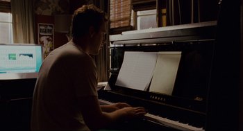 Movie still from “Forgetting Sarah Marshall” (2008), directed by Nicholas Stoller – A man sitting in front of a piano keyboard; Medium shot, Over the shoulder angle