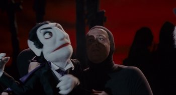 Movie still from “Forgetting Sarah Marshall” (2008), directed by Nicholas Stoller – A person holding a puppet in a dark room; Medium shot, Low angle