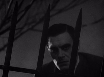 Movie still from “Frankenstein” (1931), directed by James Whale – A black and white photo of a man behind a fence; Close Up shot, Low angle